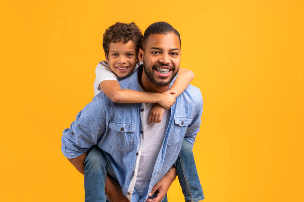 istock Happy black father and son sharing heartwarming hug against yellow studio background 2154645073