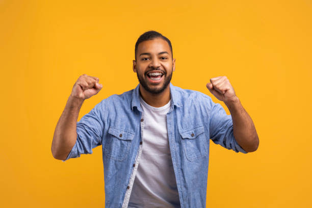 istock Joyful young black man celebrating success on yellow studio background 2154645090