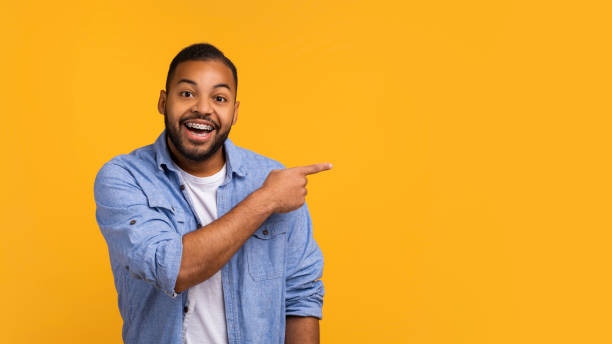 istock Look There. Excited African American Man Pointing Finger Aside, Showing Blank Space 2154645103