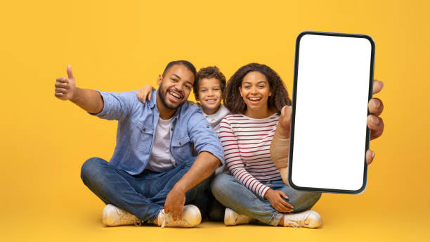 istock We Recommend. Smiling black family holding cell phone with white blank screen 2154645189