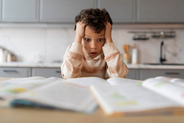 istock Shocked Black Schoolboy Touching Head While Sitting At Desk With Books 2154646451