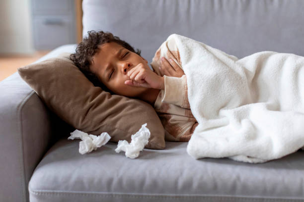 Sick black boy feeling unwell at home, coughing into fist