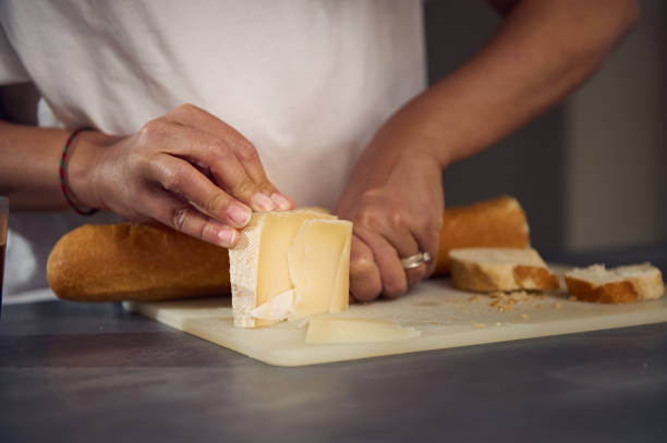 istock Close-up hands of a woman slicing cheese on cutting board, using a kitchen knife, preparing sandwiches for a healthy breakfast 2154660744