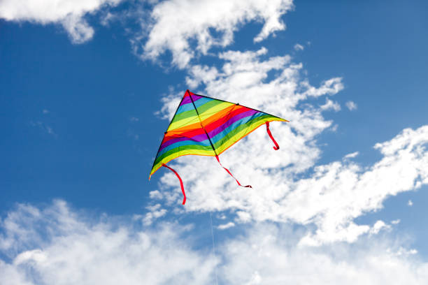 Kite flying in blue sky. Rainbow symbol