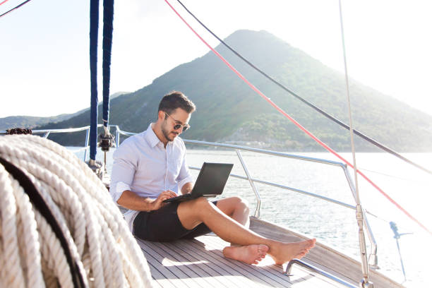 istock Man working on yacht office with laptop. Traveling on sailboat. Traveler using tablet computer. Freelancer 2154664770