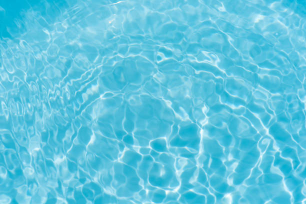 Close-up on blue rippled clean transparent water background with palm  shadow, top view