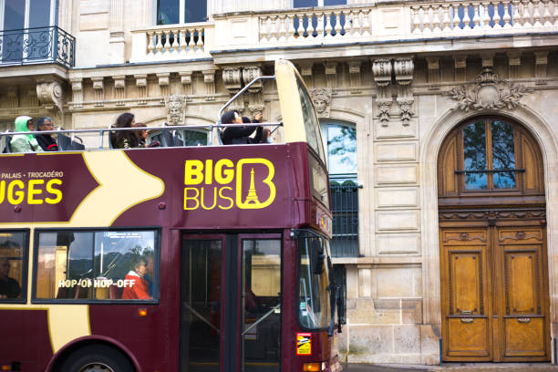 Paris, France: Tourists ride on an open-air tour bus in the 7th arrondissement near the Eiffel Tower. The tour bus company is called Big Bus Tours.