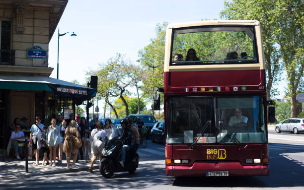 Paris, France: Tourists ride on an open-air tour bus in the 7th arrondissement near the Eiffel Tower. The tour bus company is called Big Bus Tours.