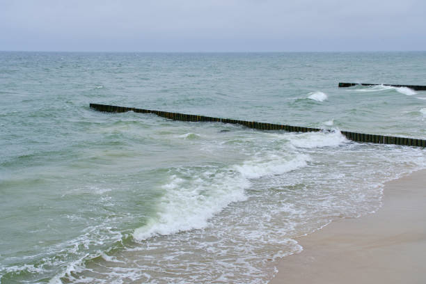 Wave breaks on the pier of the sunny Baltic Sea.
