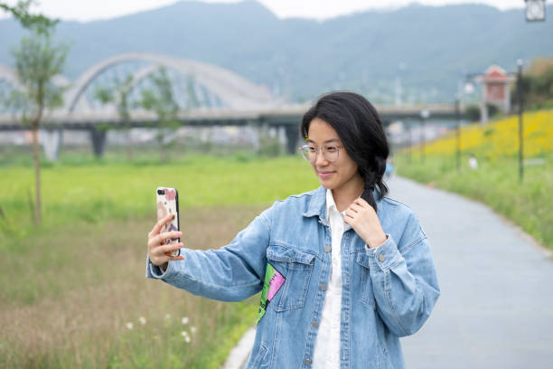 istock Girl taking selfie with mobile phone in park 2154675320