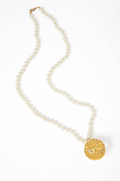 Close-up of pendant with bird sculpture and pearl on white background.