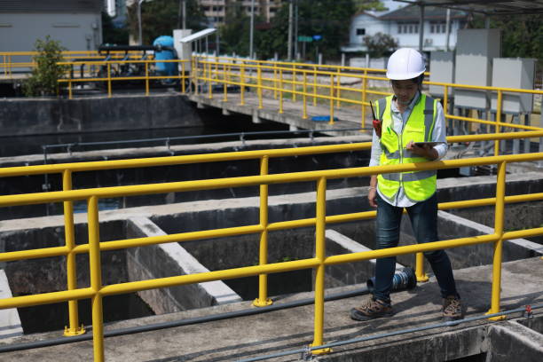 istock Workers under checking the wastewater treatment pond industry to control the water support industry. Engineer takes water from the wastewater treatment pond to check the quality of the water 2154683497