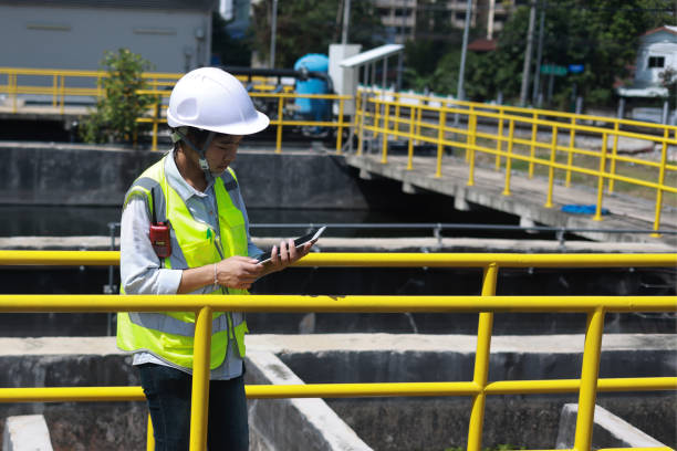 istock Workers under checking the wastewater treatment pond industry to control the water support industry. Engineer takes water from the wastewater treatment pond to check the quality of the water 2154683498