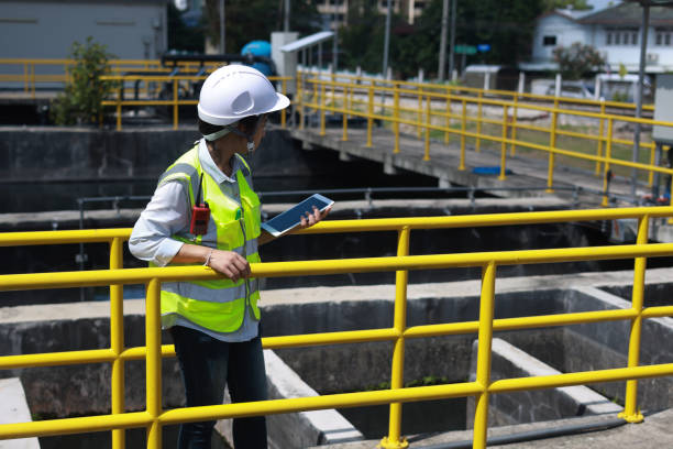 istock Workers under checking the wastewater treatment pond industry to control the water support industry. Engineer takes water from the wastewater treatment pond to check the quality of the water 2154683513
