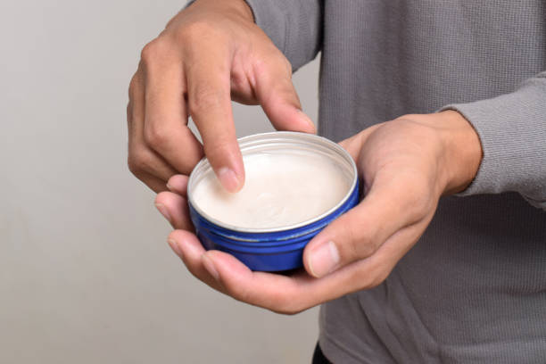 Man's hand holding pomade or waxe for hair styling isolated on white background