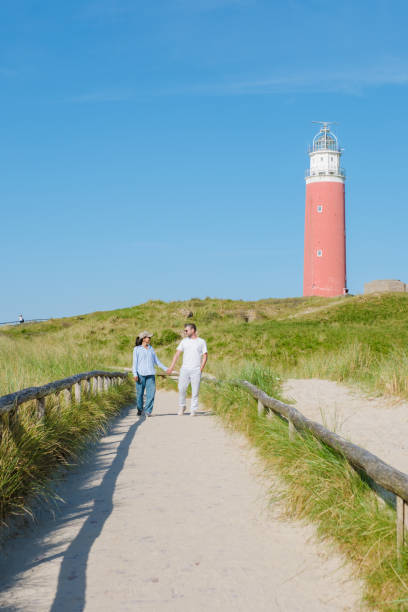 istock A peaceful scene unfolds as two individuals stroll along a path near a charming lighthouse in Texel, Netherlands 2154693644