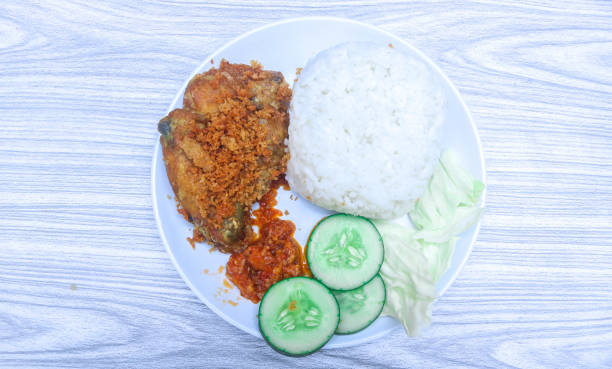 istock Fried chicken bone soft (ayam tulang lunak) served with rice, chili sauce and fresh vegetables in a white plate isolated on white background 2154694914