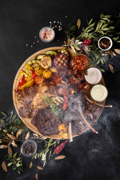 istock Delicious Assorted Grilled Meat Feast with Vegetables, BBQ Ribs, Lamb Chops, Beef, Turkey, Chicken on Charcoal Grill 2154700396