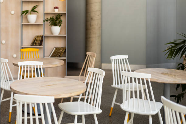 istock Modern restaurant interior background. An empty wooden table and chairs in a cafe. The cafe is filled with furniture such as white chairs and tables 2154700832