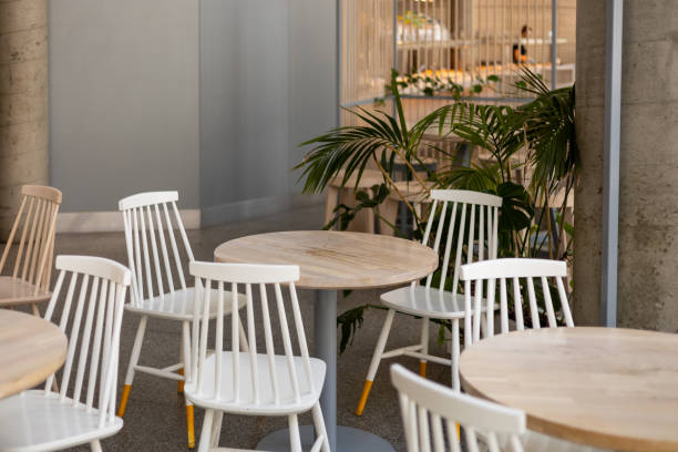 istock Modern restaurant interior background. An empty wooden table and chairs in a cafe. The cafe is filled with furniture such as white chairs and tables 2154700842