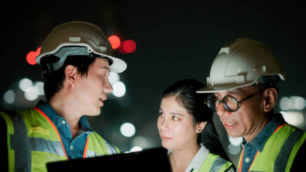 istock Business people, architect and tablet in construction planning, meeting or collaboration on site at night. 2154702085