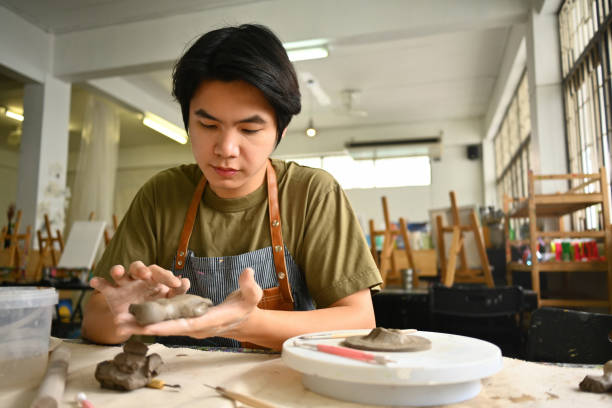 An artist concentrates on shaping clay in a well-equipped studio, showcasing the creative process of handmade pottery. The image captures dedication, craftsmanship, and the artistic environment