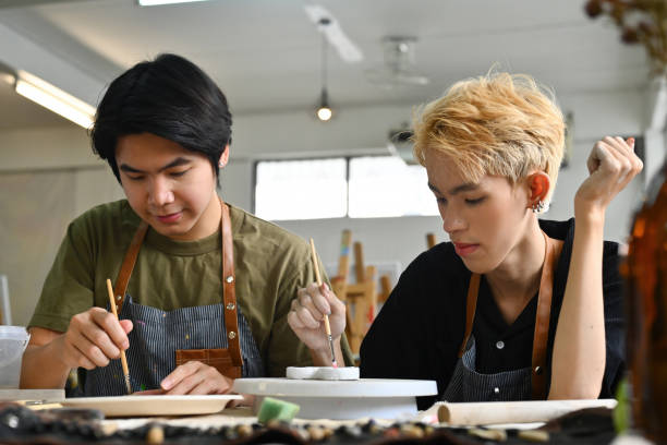 istock Two students focused on painting ceramic pieces in an art classroom 2154703298