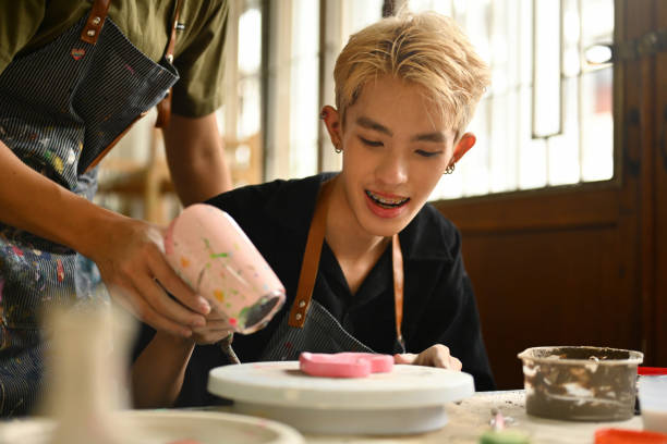 istock Young Artist Enjoying Pottery Making with a Helping Hand in a Creative Workshop 2154703501