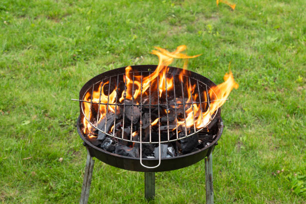 istock metal grill on sunny spring day green grass with burning coals and big flame 2154703654