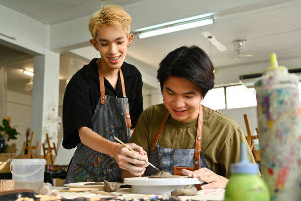 istock A student joyfully learns pottery with guidance in a creative studio. The image captures the hands-on process of sculpting clay, highlighting the collaborative and educational aspects of art 2154704107