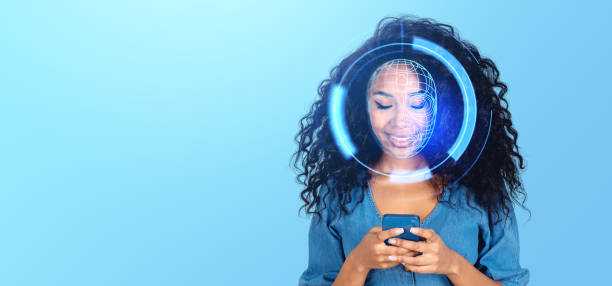 istock A smiling woman with digital face recognition graphics over her face, holding a phone, on a blue background, depicting cybersecurity concept 2154704109