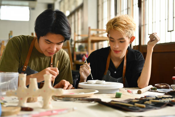 istock Two students concentrate on painting ceramic pieces in an art studio. They work side by side, sharing tools and techniques, fostering creativity and collaboration 2154704800