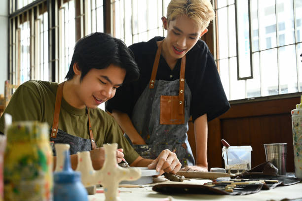 istock Two artists, one teaching and one learning, share a moment of joy while working on pottery. The image captures the creative learning process and the collaborative spirit of art education 2154704848