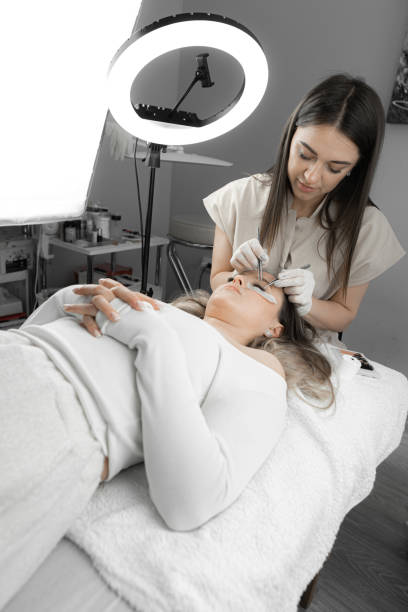 istock The photo shows the procedure for eyelash extensions from a professional lashmaker in a beauty salon. The woman lies relaxed, and beautician applies soft artificial eyelashes, giving her charming look 2154704898