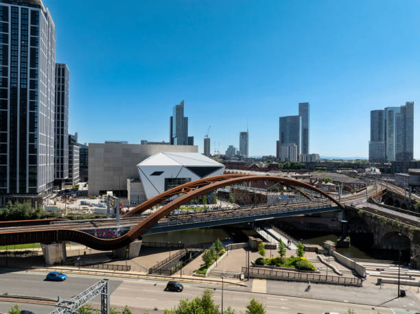 An aerial photograph of Ordsall Chord Railway Bridge in Downtown Salford in Northwest England. Salford is a city which sits on the edge of Manchester and whilst this section of the railway in the foreground is in Salford, the skyscrapers in the distance are in downtown Manchester. The photograph was produced on a bright, cloudless summer day.