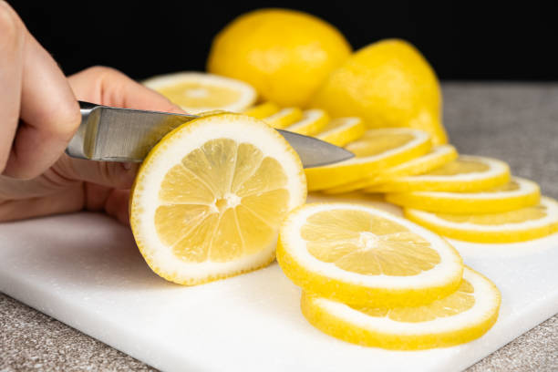 istock Woman cutting lemon into slices with a sharp utility knife on a stone kitchen board. 2154712388
