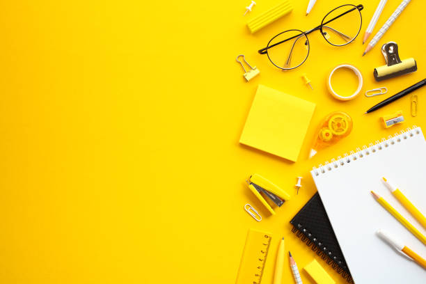 istock Flat lay composition with office supplies on yellow background. A neatly arranged collection of office essentials, including eyeglasses, pens, sticky notes, pencils 2154713252