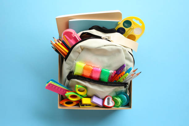 istock Donation box with backpack with school supplies on bright blue background. 2154713516