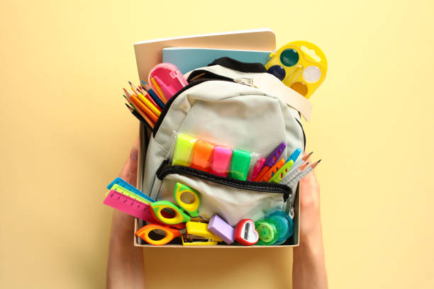 istock The woman's hands hold a donation box with a backpack containing various school supplies. Donation concept. 2154714130