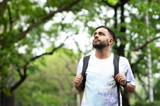 istock Young handsome man with backpack exploring the nature park 2154716842