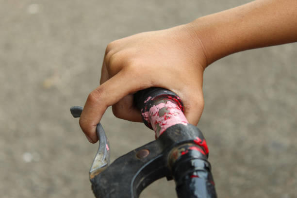 Zoomed in photo of woman's hand holding a bicycle handle while being outdoors.