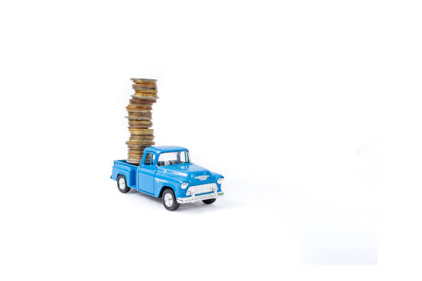 Die cast pickup toy carrying  a high stack of coins, isolated on white background, soft focus