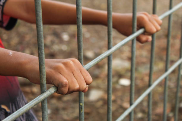 istock hand holding iron fence close up 2154724297