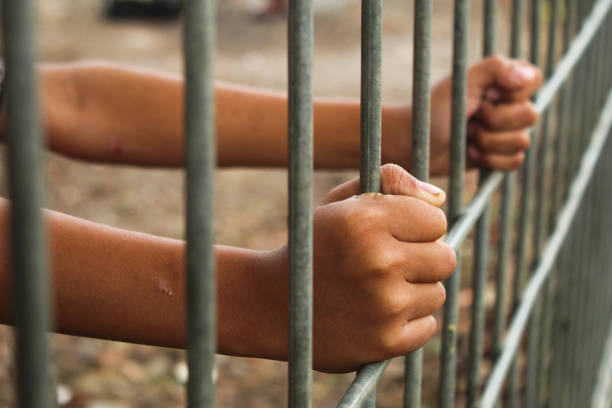 istock hand holding iron fence close up 2154724317