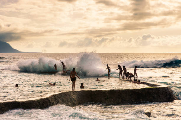 Young people enjoying with the waves at the natural swimming pools of La Maceta in El Hierro, created with sea water among the volcanic rocks (Canary Islands, Spain)