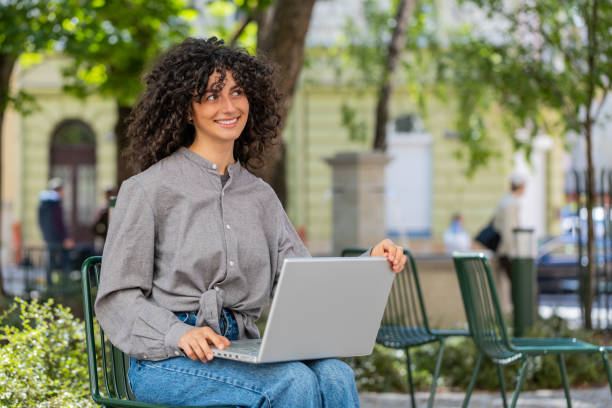 istock Woman freelancer working online distant job with laptop browsing website sitting on city street 2154732012