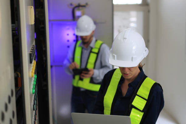 istock Industrial service electrician engineers stand side by side, exchanging ideas in front of the electricity control board. Energy management system (EMS) concept Main Distribution Board 2154733078