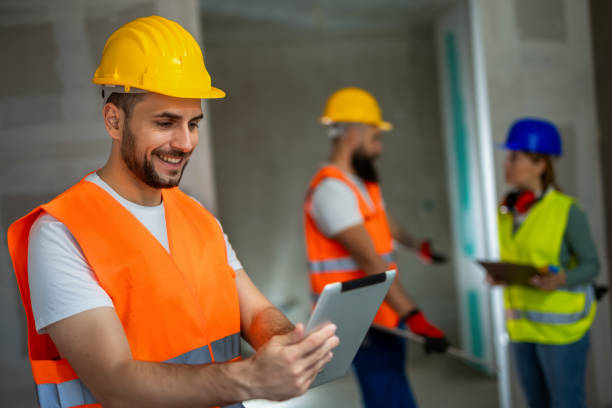istock Construction site manager standing  wearing safety vest and helmet, holding a tablet. 2154735254