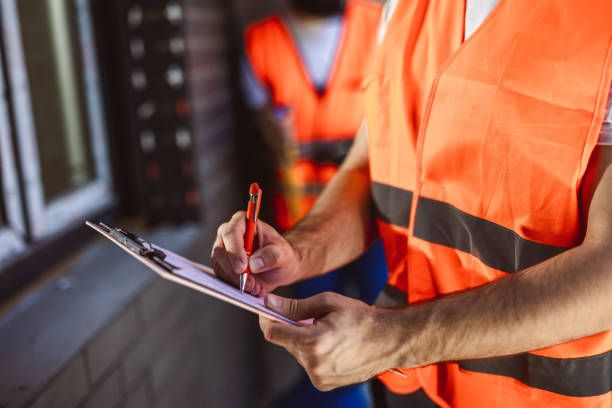 istock Construction site manager standing  wearing safety vest  and writing on paper. 2154735562