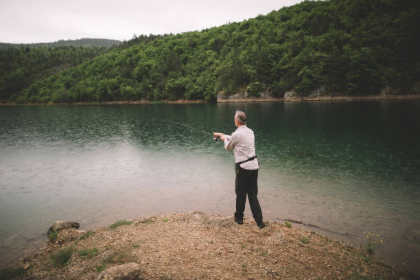 A nice girl admires the mountain landscape, from Green Lake in Vallee Etroite, pretending to fish in the clear green waters of the lake. She is breathing in the pure air of the larch forest.